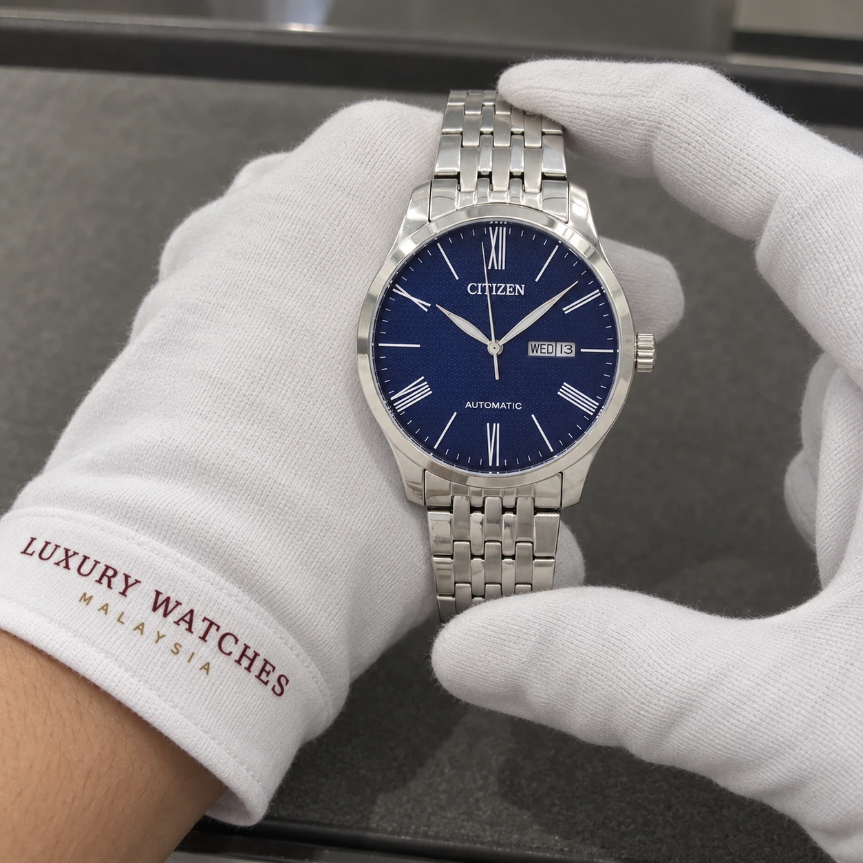 Citizen NH8350-59L presented in white gloves with a Luxury Watches Malaysia cuff mark