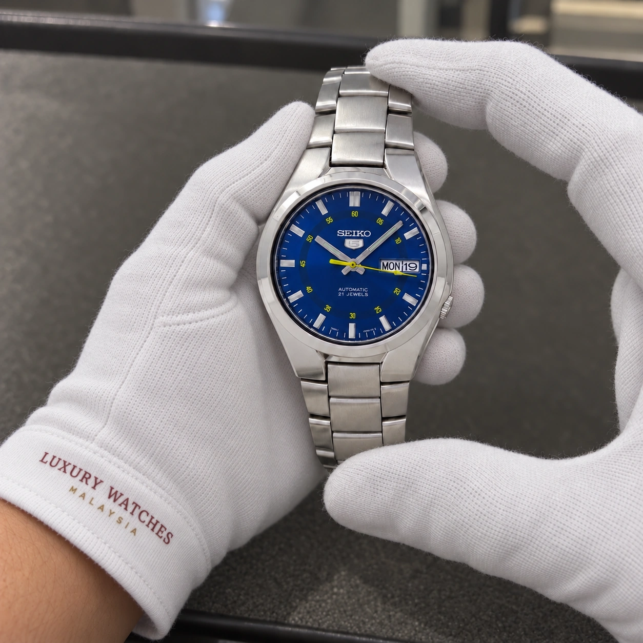 Seiko SNK615K1 presented in white gloves with a Luxury Watches Malaysia cuff mark