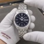 Seiko SNKL23K1 held in white cotton gloves with Luxury Watches Malaysia cuff mark