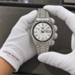 Seiko SNXS73K1 held in white cotton gloves with Luxury Watches Malaysia cuff mark