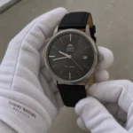 Orient Bambino FAC0000CA0 grey dial watch in branded white cotton gloves under soft low-glare lighting
